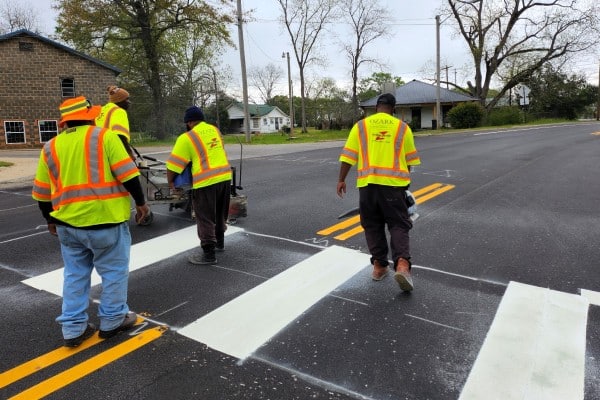 Ozark Striping crew applying high-visibility crosswalk markings on a residential street as part of a roadway safety project